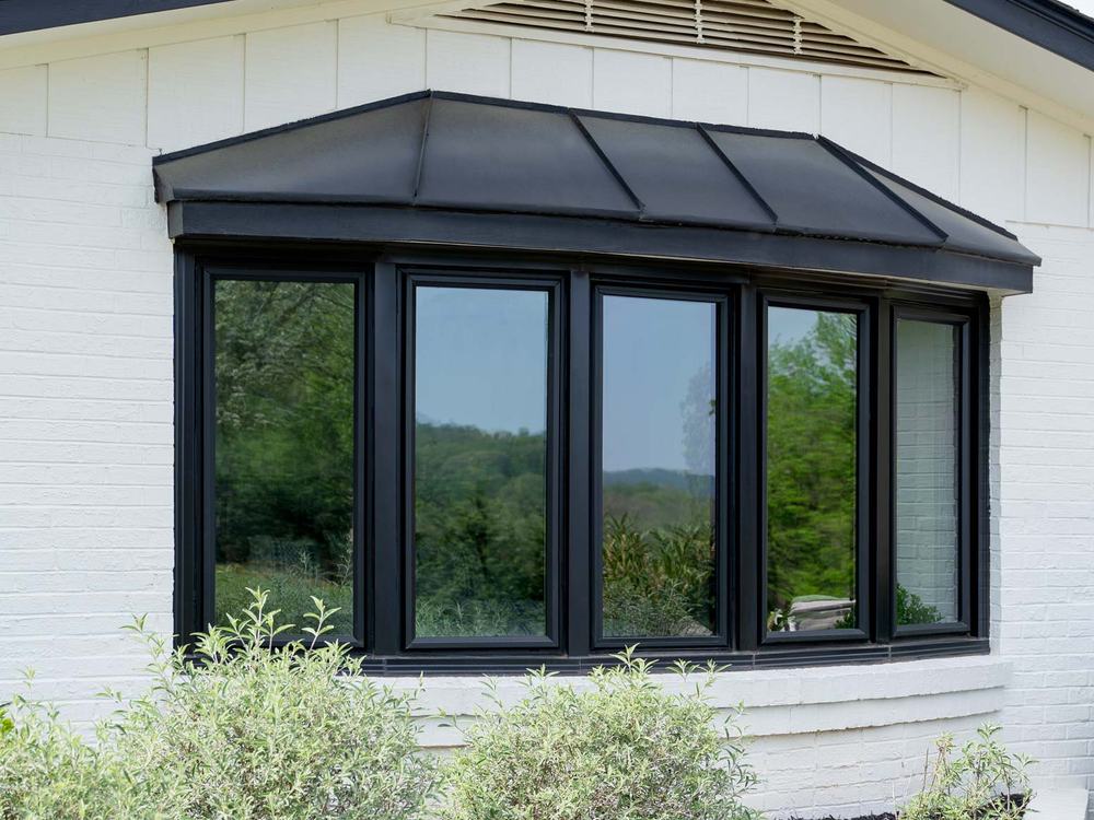 A home with a new ProVia bow window installed above the front landscaping